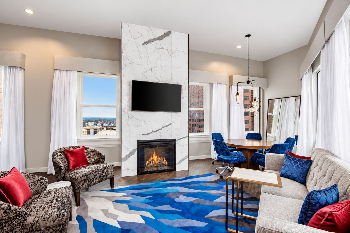 Hotel suite living room with a marble fireplace, lounge seating and city views